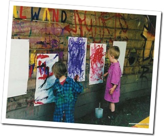 Kinder malen an einer Holzwand